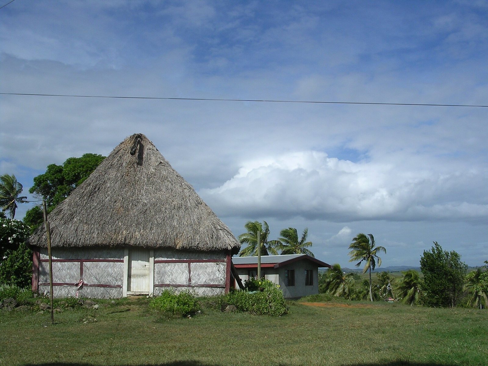 A chief's thatched bure standing among palms in a coastal Fijian village